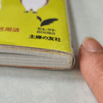 本の横に指を置いてうすさをわかりやすくした画像