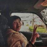 送迎の車の中でピースサインをする母の画像