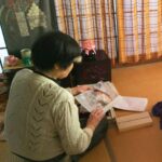 和室で、箱や引き出しの中を全部出して、見ている母の画像。