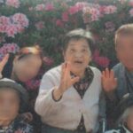 満開のツツジの前で、小規模多機能型居宅介護施設の職員と利用者と母の記念撮影の画像